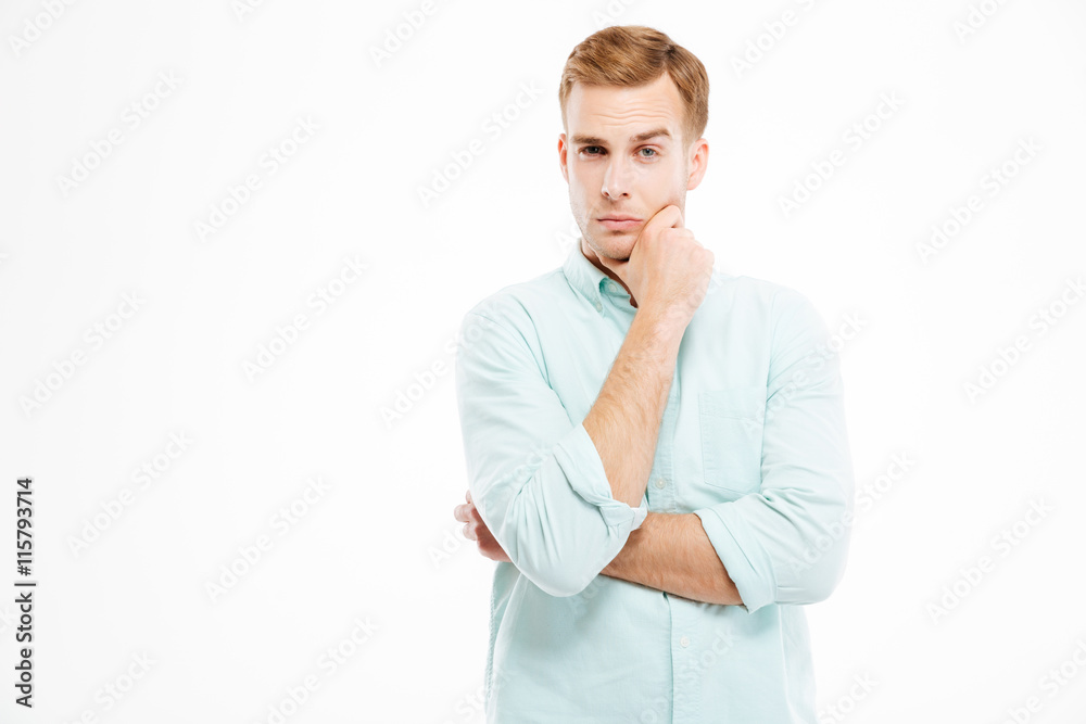Pensive handsome young businessman stading with hands folded and thinking Pensive handsome young businessman stading with hands folded and thinking
