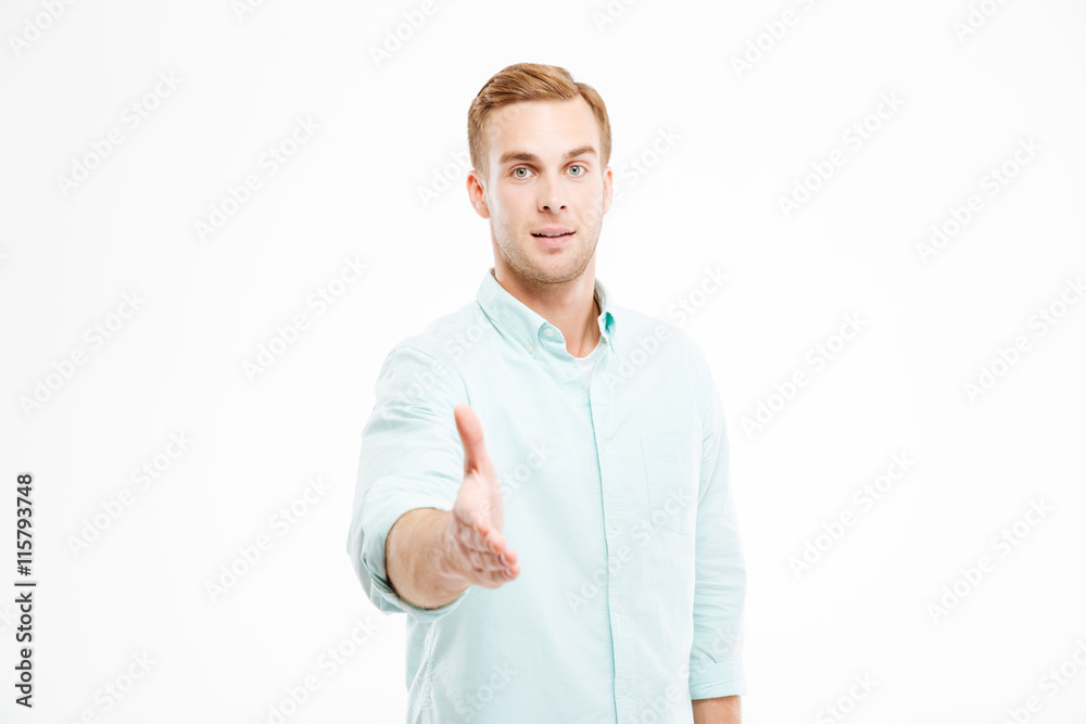 Attractive young businessman standing and giving his hand for handshake Attractive young businessman standing and giving his hand for handshake