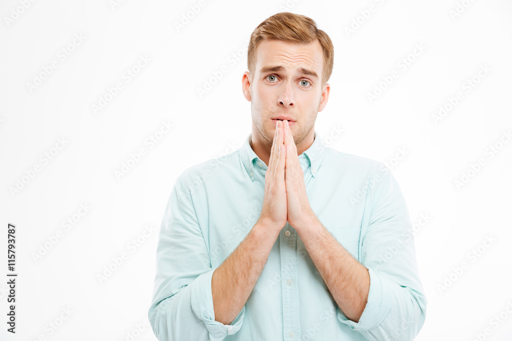 Handsome young businessman standing and praying Handsome young businessman standing and praying
