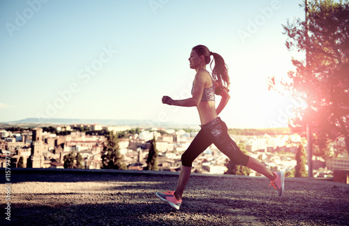 Running athletic female exercising at sunset outdoors. Concept of sport, fitness and lifestyle. 