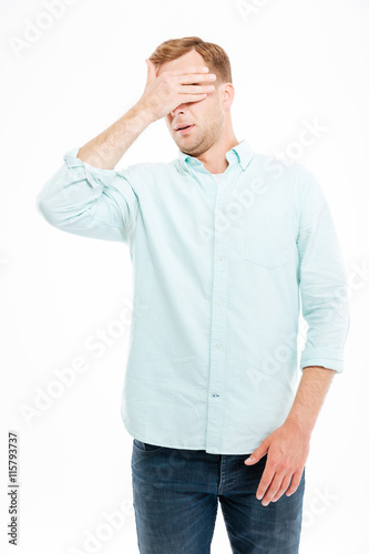 Handsome young businessman covered his eyes by hand