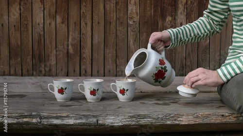 Woman pouring tea into three mugs photo