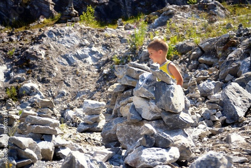 Little cute boy building tower of stones