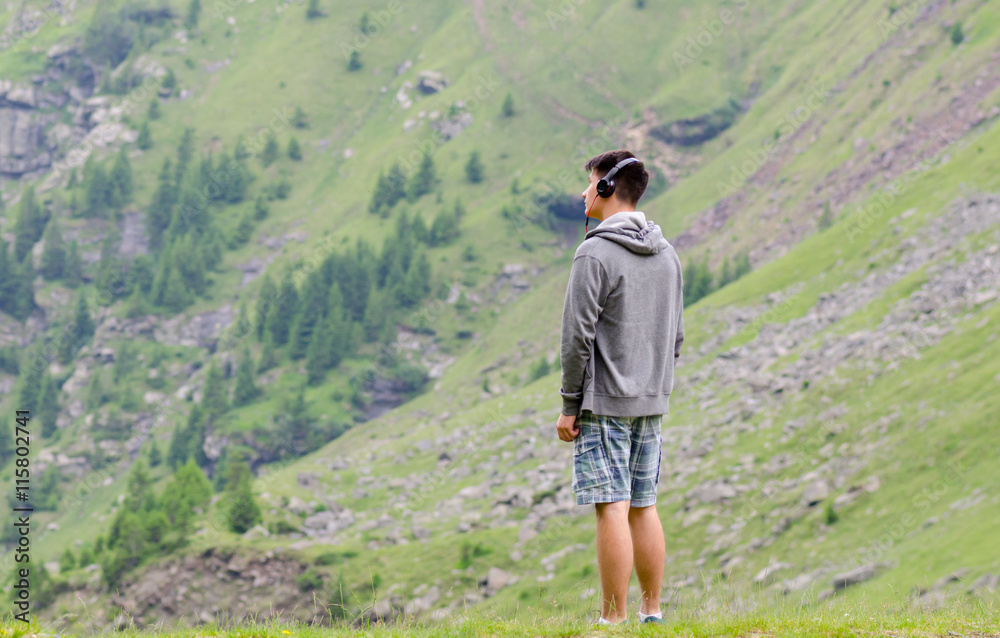Naklejka premium Teenager man with headphones listen to music melacholic at mount