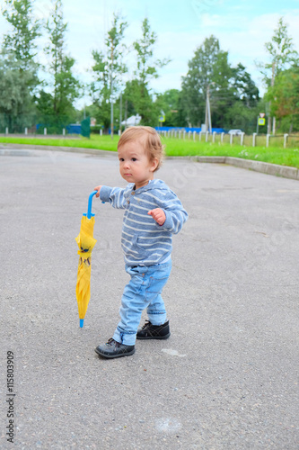 one year old European kid walking with a folded umbrella © sergeevspb