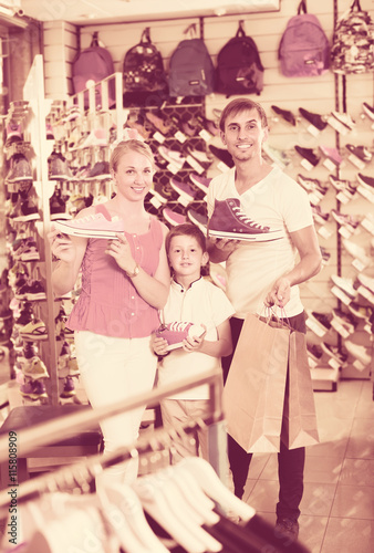 Family choosing shoes in sport shop.