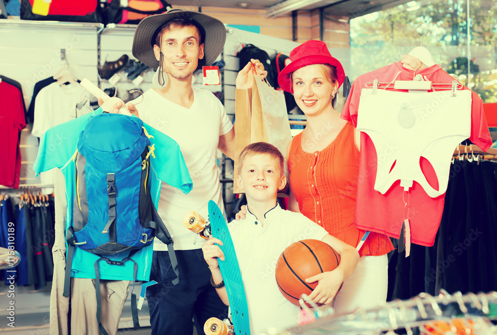 Smiling parents with boy shopping hiking goods
