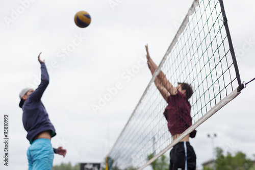 Blurred volleyball players jump to attack and block.