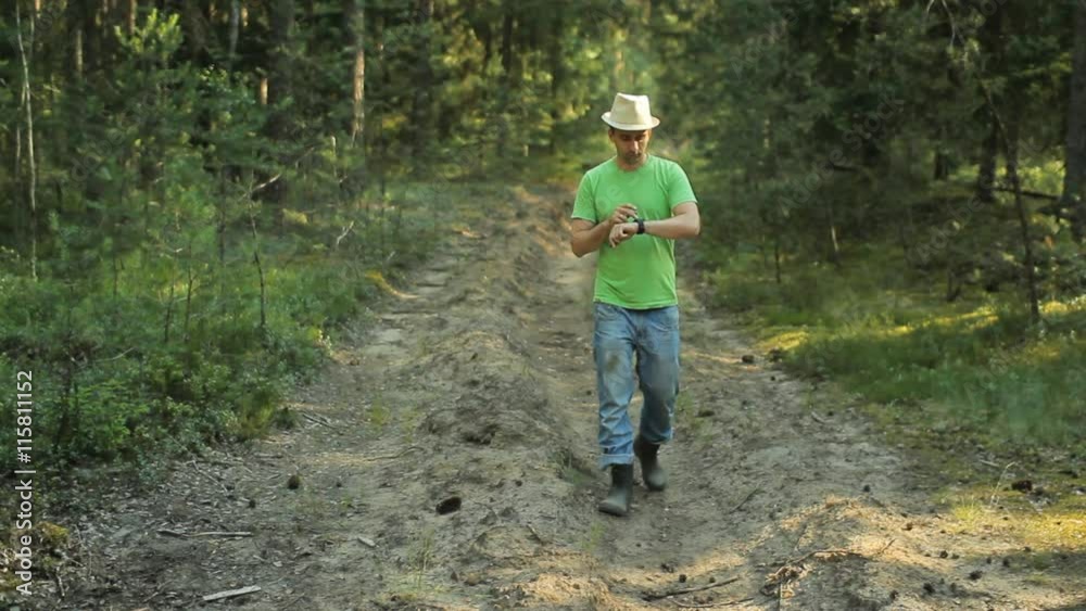 A man walks through the forest with smart watch and looking at the navigation application. He chooses the right direction A man walks through the forest with smart watch and looking at the navigation application. He chooses the right direction