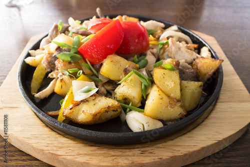 fried potatoes with meat and tomatoes in a cast iron skillet