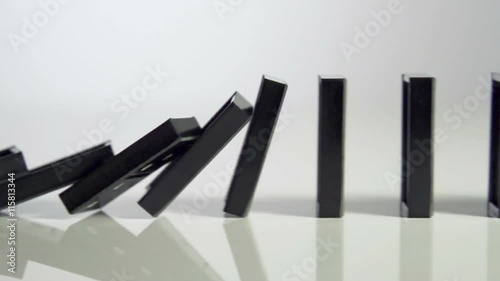 Row of dominoes with one falling over