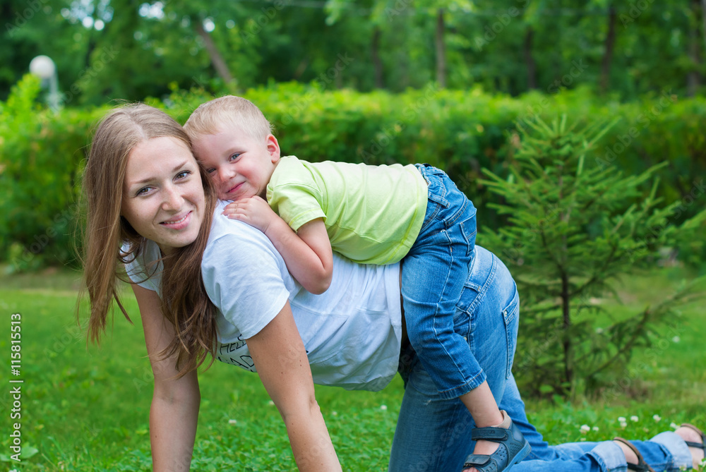 Fototapeta premium Cheerful Smiling Mother and Boy playing on her Back