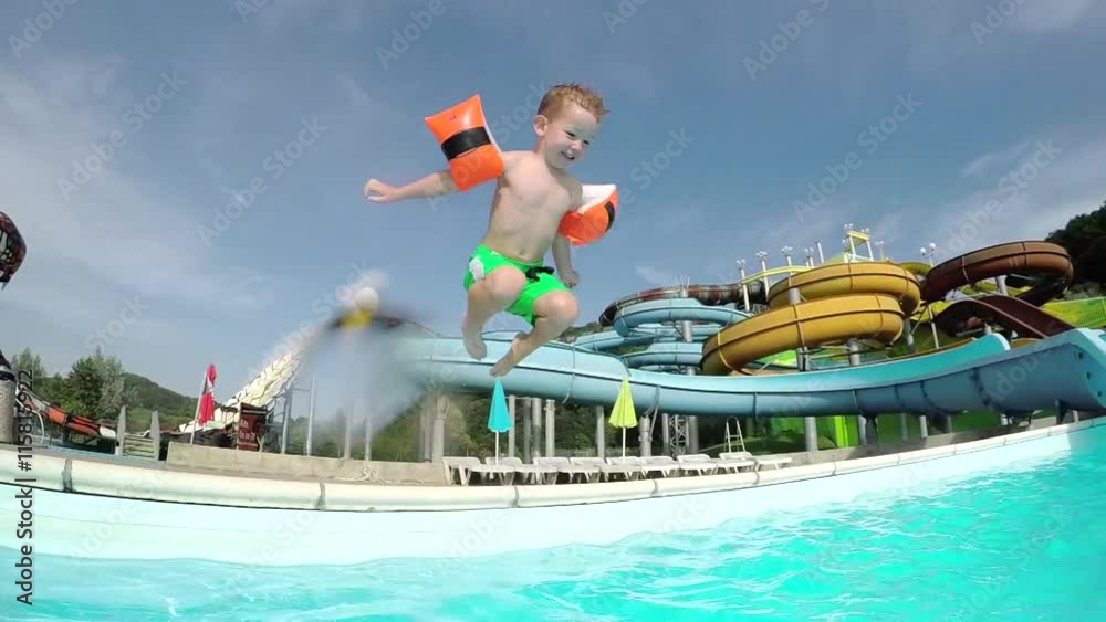 SLOW MOTION: Happy kid smiling and jumping into pool water