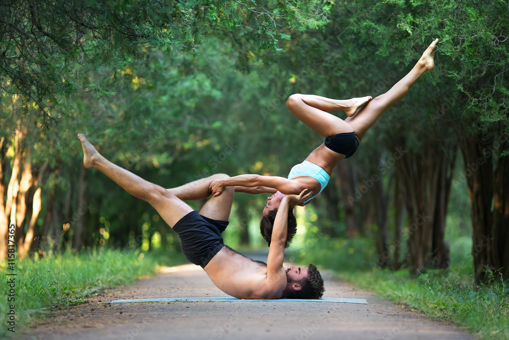Fotografia Acro yoga, two sporty people practice yoga in pair