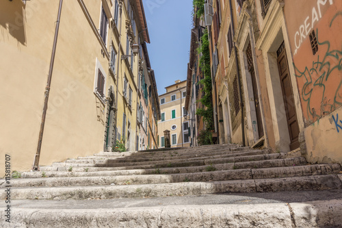 Gasse in Rom mit Treppe und einem Trinkbrunnen in der Bildmitte aus einer Untersicht