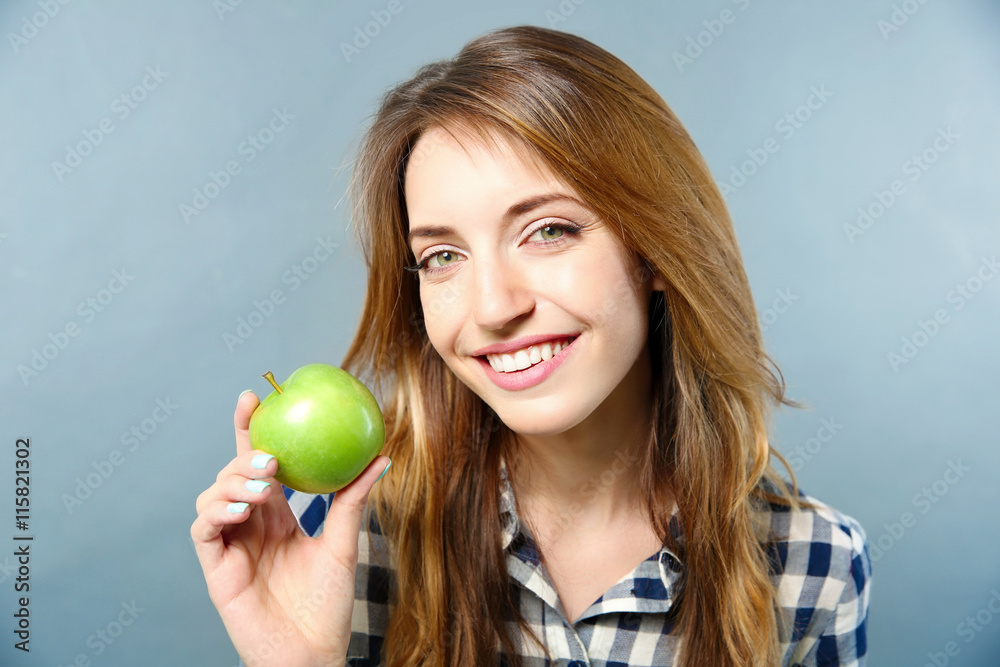 Beautiful girl with green apple on grey background Beautiful girl with green apple on grey background