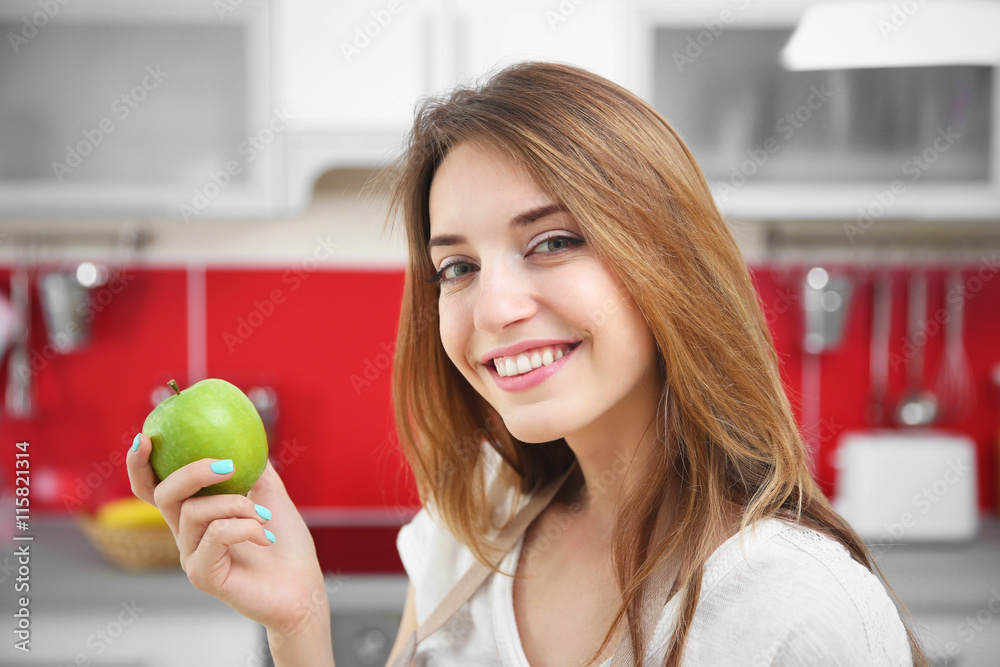 Beautiful girl eating apple in kitchen Beautiful girl eating apple in kitchen