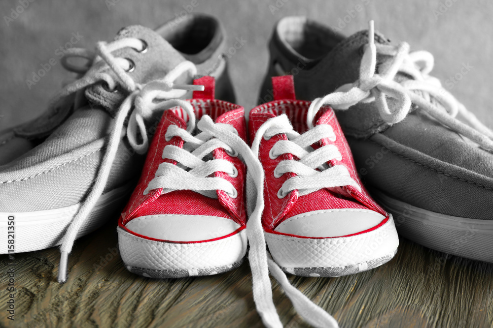 Big and small shoes on wooden table Big and small shoes on wooden table