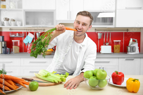 Handsome man eating carrot ...