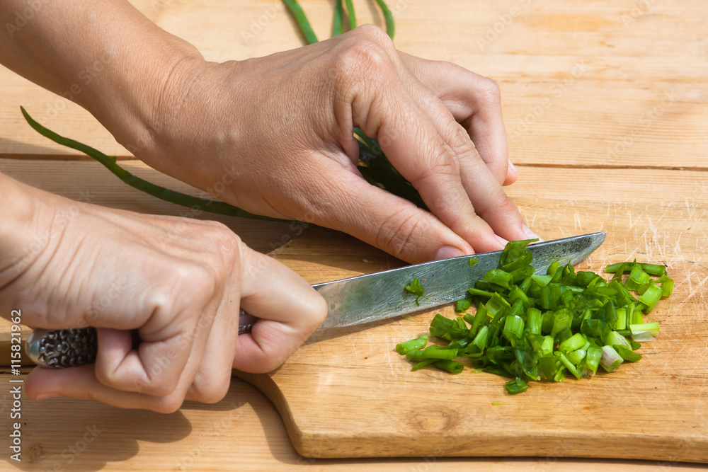 hands chopping green onion on the cutting board hands chopping green onion on the cutting board