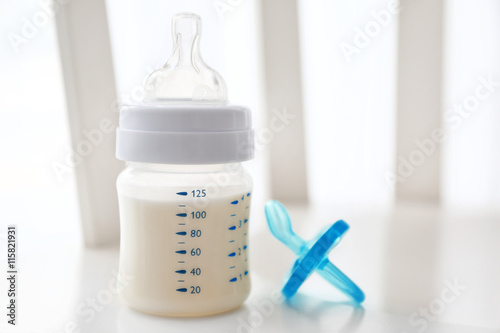 Baby milk bottle and pacifier on white background