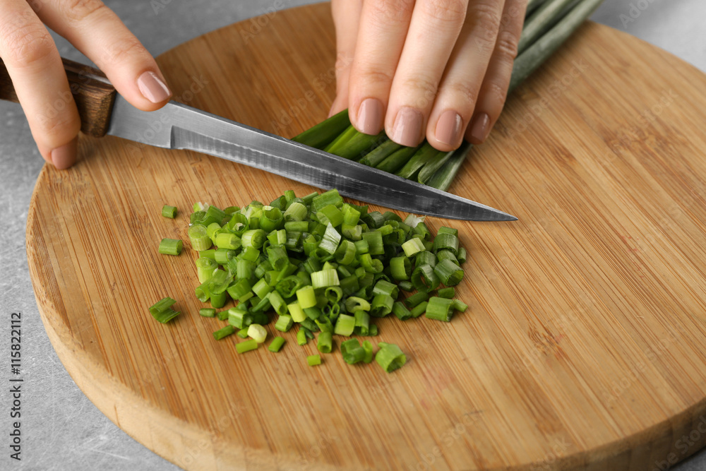Female hands cutting onion on wooden board Female hands cutting onion on wooden board