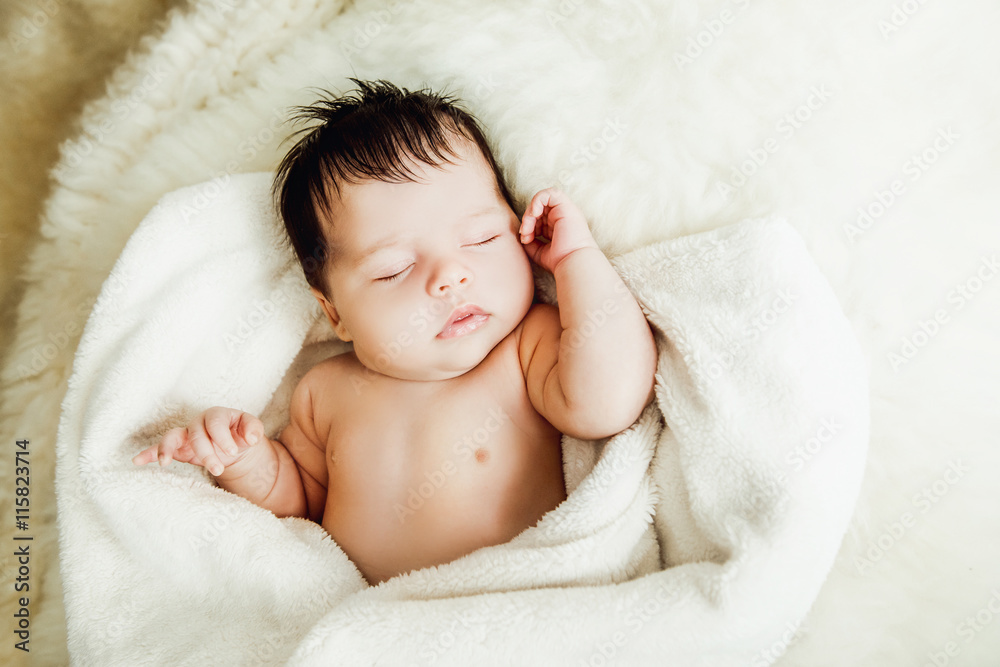 Newborn baby girl sleeps wrapped in white blanket. Newborn baby girl sleeps wrapped in white blanket.