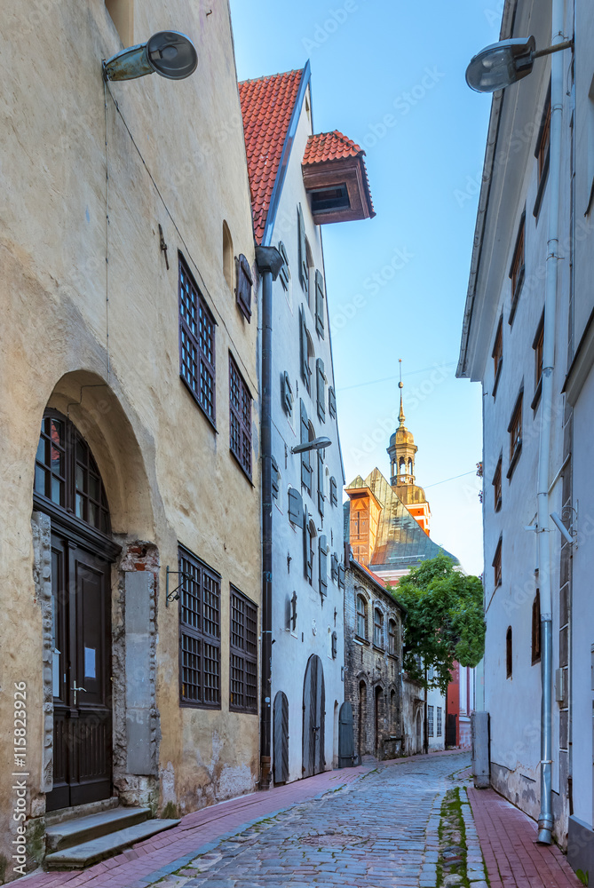 Narrow street in old Riga city, Latvia. Walking through medieval streets of old Riga tourists can feel unforgettable atmosphere of the Middle Ages
