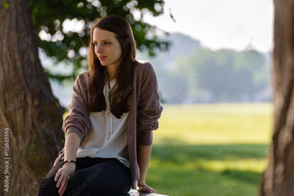 The portrait of the beautiful girl sits on a bench in green park The portrait of the beautiful girl sits on a bench in green park