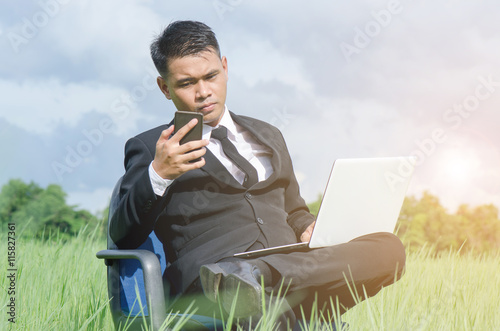 Manager, Business man sitting at a chair in the middle of a meadow in suit. photo