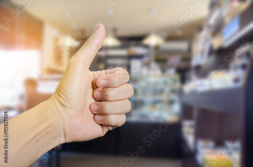 Fotografija Man hand showing thumbs up in coffee shop