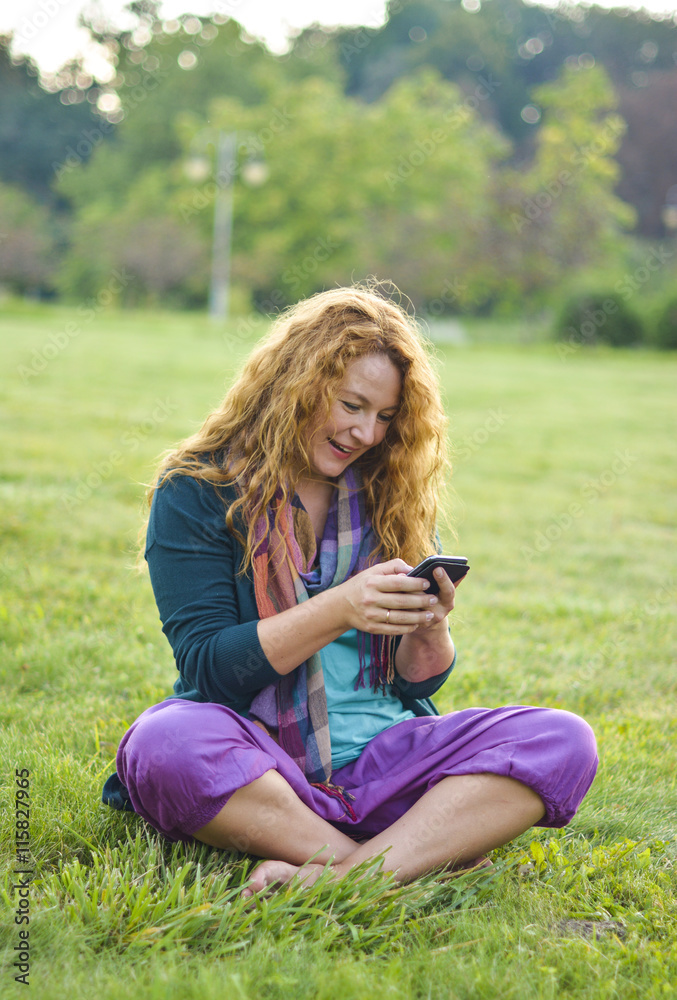 Fototapeta premium woman talking on phone top of the grass