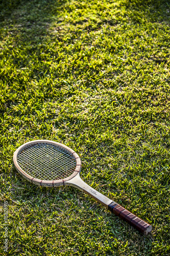 Vintage wood tennis racket on green grass garden