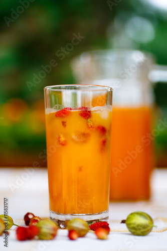 Orange drink is poured into a glass and decanter.