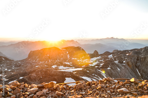 Spectacular sunrise seen from the summit of Hochkoenig mountain (Austria) at 2941m above sea level in the Berchtesgaden alps. Dachstein group in background. Image cross processed.Lens flares from sun. photo