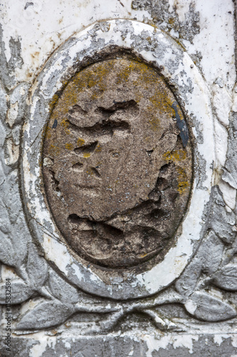 Old gravestone with damaged portrait of the buried person