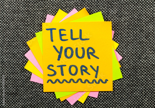 Φωτογραφία tell your story suggestion on a sticky note against fabric texture