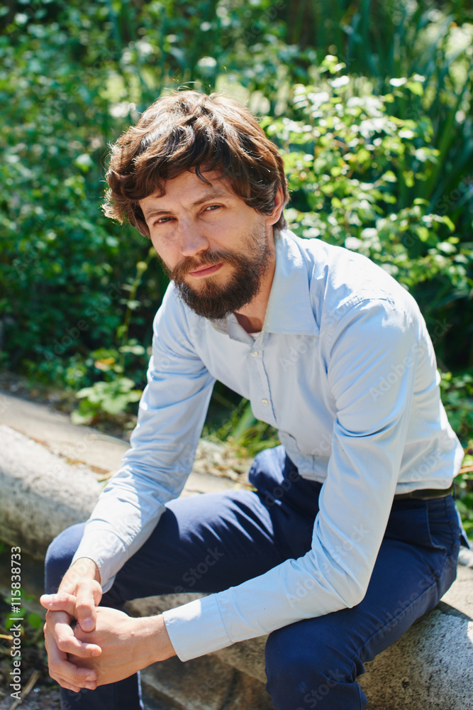 Portrait of a man in shirt and trousers sitting in a Park Portrait of a man in shirt and trousers sitting in a Park