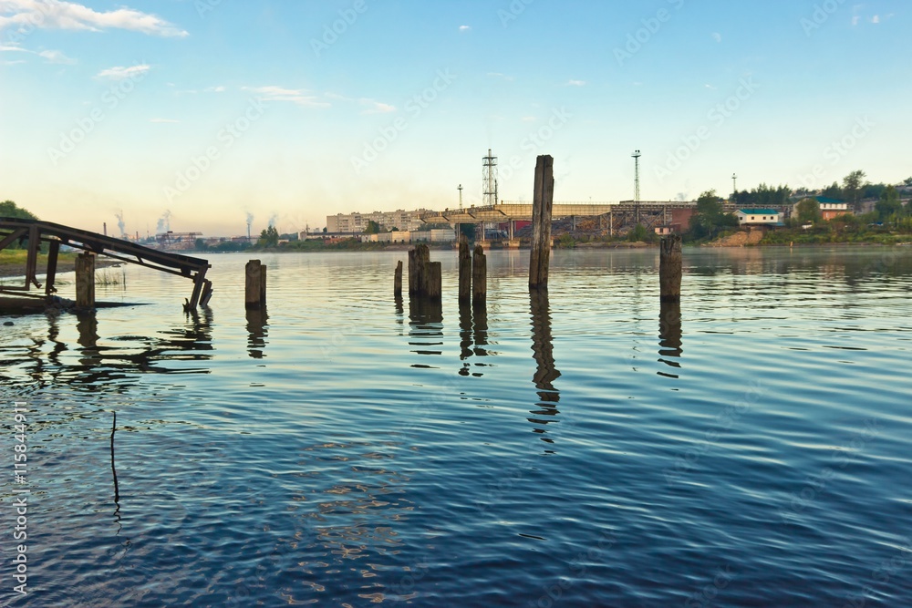 Old broken pier in river at sunrise