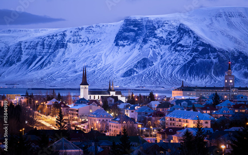 Illuminated City skyline with mountain backdrop at dawn, Reykjavik, Iceland