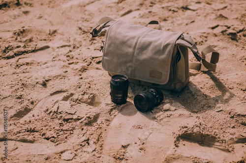 Bag photographer and lenses in the sand