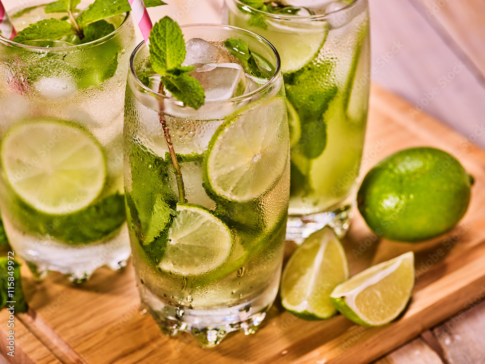 Alcohol drink. On wooden boardsthree glasses with alcohol cocktail drink and ice cubes. Drink hundred sixty one cocktail mohito and cube ice with straw. Country life. Top view. Light background. Alcohol drink. On wooden boardsthree glasses with alcohol cocktail drink and ice cubes. Drink hundred sixty one cocktail mohito and cube ice with straw. Country life. Top view. Light background.