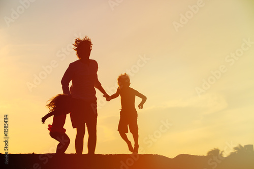 happy father with son and daughter jumping at sunset