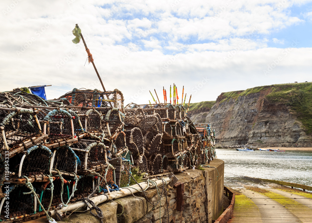 STAITHES, ENGLAND - JULY 12: Lobster fishing pots stacked up on the quayside. In Staithes, North Yorkshire, England. On 12th July 2016.