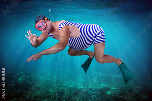 diver in retro swimsuit shows gesture O.K. under water