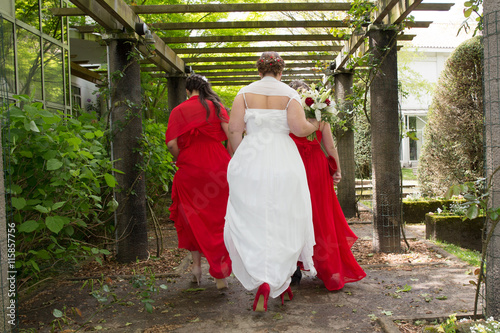 Bridesmaids walking and looking after bride red and white dress