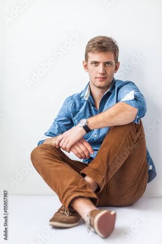 Handsome serious man sitting on the floor