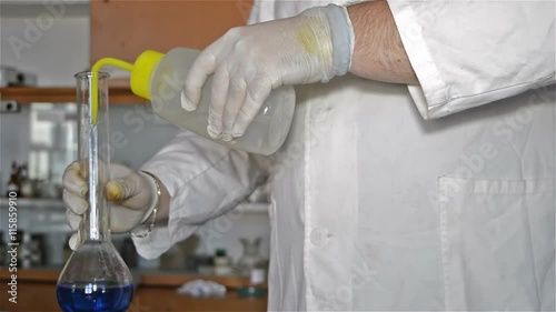 Close-up hands in gloves of the lab tehnician in the white coat dilution blue liquids in the laboratory experiment. photo