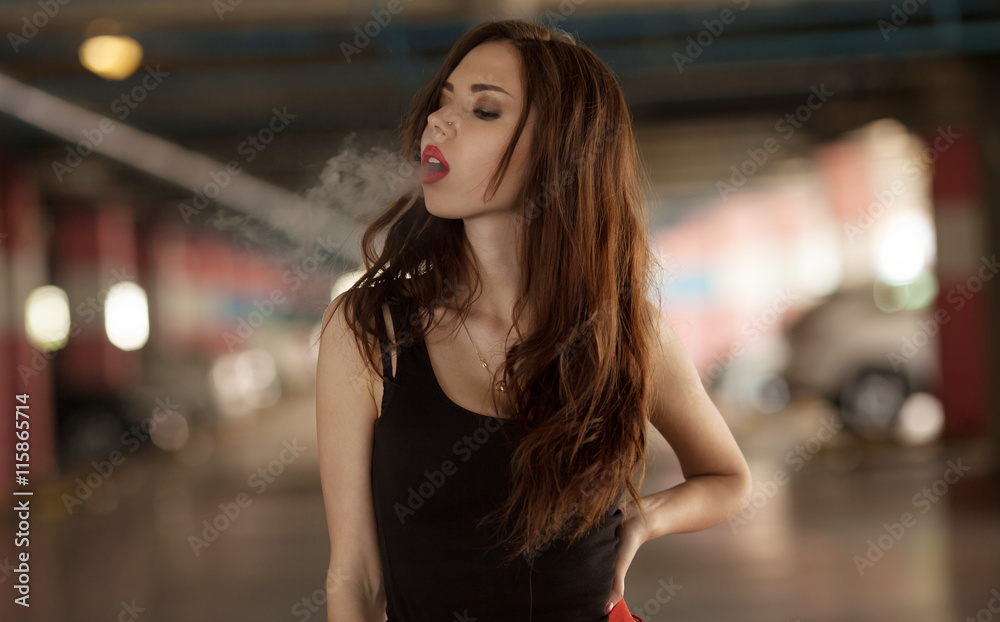 Young beautiful woman smoking ( vaping ) e-cigarette with smoke