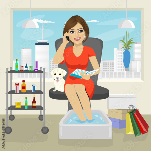 Beautiful woman getting spa pedicure procedure talking on smartphone and reading fashion magazine